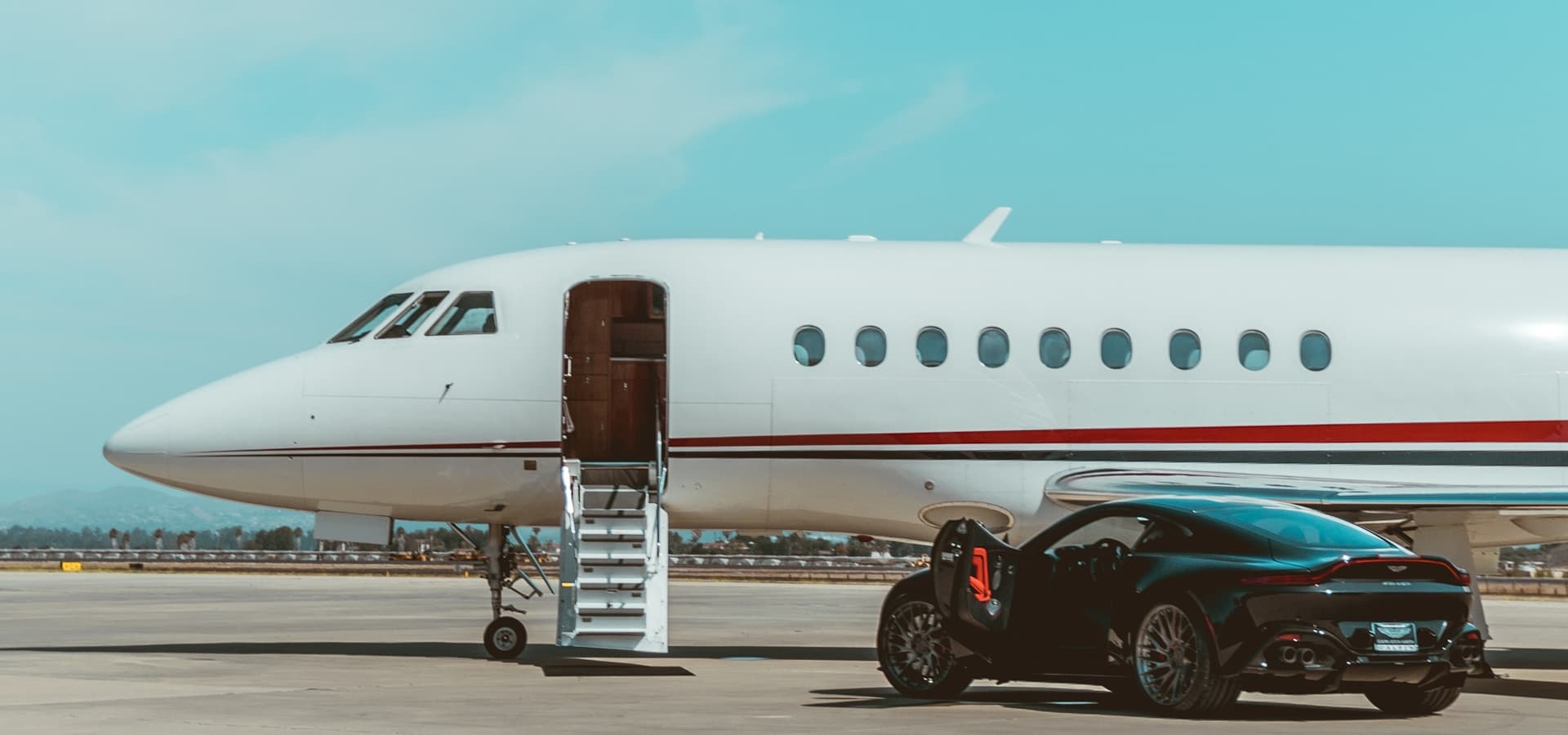 Private jet on the apron with its airstair down, a black sports car waiting alongside
